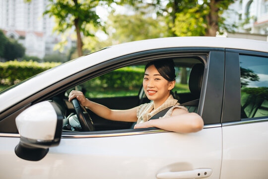 Side view of smiling young female driver driving car looking away