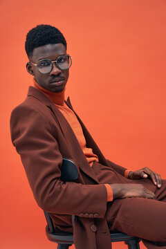 Fashionable male model in brown suit posing in studio