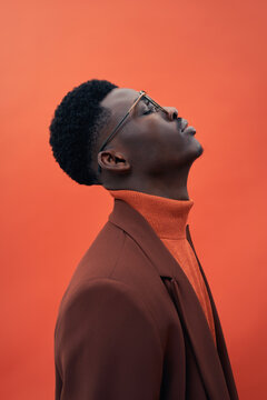 A fashionable male model in a brown suit and stylish glasses 