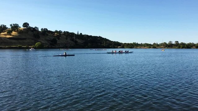 Handheld Shot Of People Rowing In Various Boats On Lake In Folsom California With Clear Blue Sky
