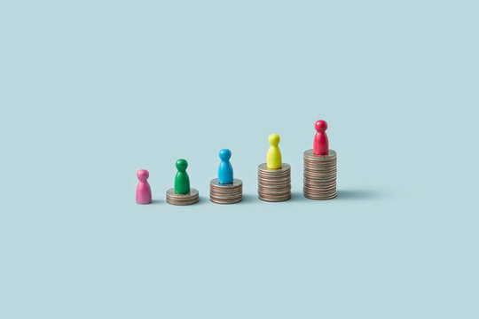 Row of game pawns of various colors on stacks of coins.