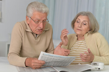 old couple portrait with newspaper at home