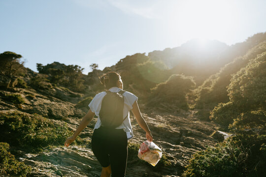 Woman Carrying Trash in Rocky Landscape
