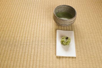 Matcha tea cup and a sweet on tatami mat for Japanese tea ceremony