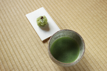 Matcha tea cup and a sweet  on tatami mat for Japanese tea ceremony