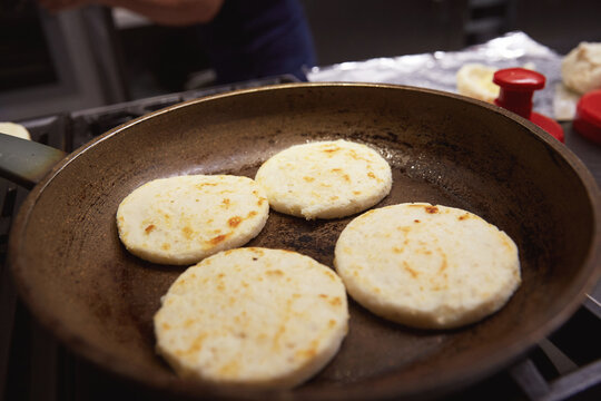 Portrait of a woman with a radiant, joyful smile as she makes arepas