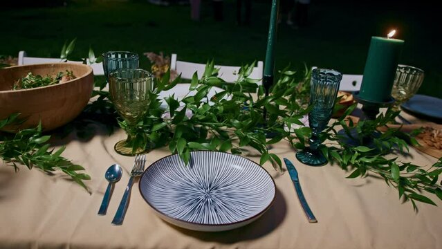 An empty plate stands on a set festive table at night outdoors