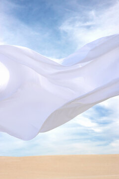 Texture of flowing white fabric against a desert background. 