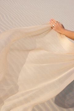 A woman's hands flying a silk fabric in the wind. 