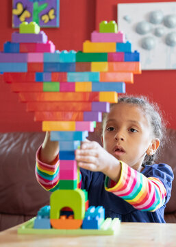 Child building a heart with bright coloured blocks.