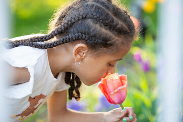 Cute child smelling a tulip in a spring garden