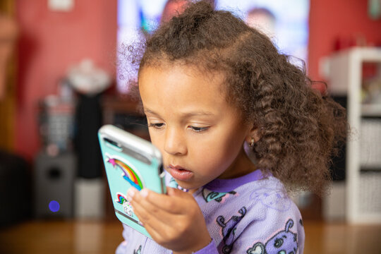 Preschool child with curly hair using an electronic phone
