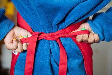 Child putting on an apron and tightening the bow behind her back