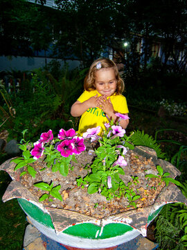 child admires flowers in flowerbed