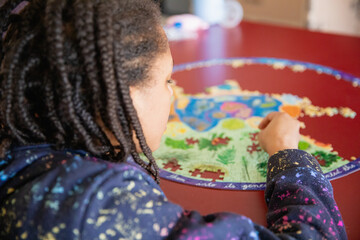 Child with cornrow braids assembling a puzzle