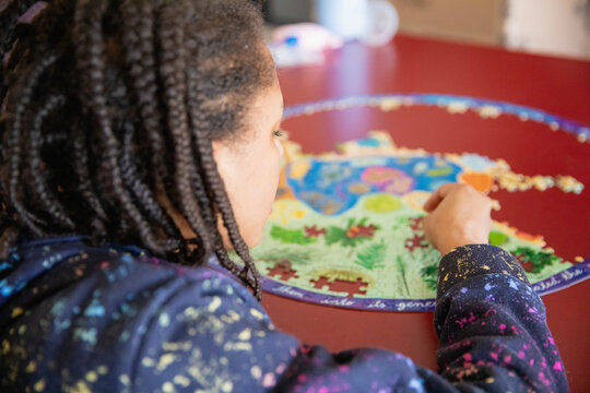 Child with cornrow braids assembling a puzzle