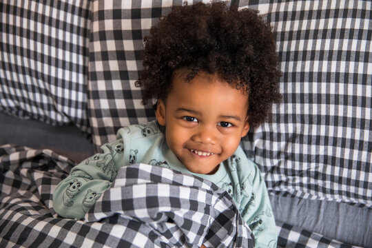 Close up portrait of a happy child lying in a bed in the morning