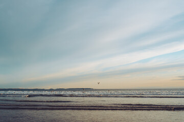 Golden hour seascape with gulls flying low over the waves