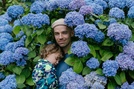 Father and little son with blue beautiful flowers