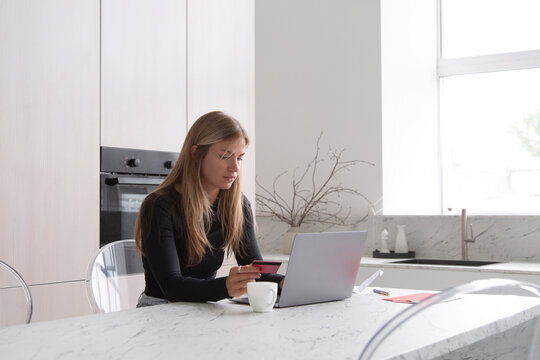 Freelancer shopping online with laptop in kitchen