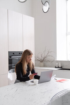 Woman with netbook and credit card in kitchen