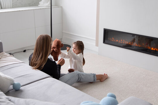 Mother and daughter playing with soft toy at home