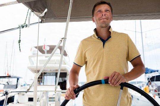 Capitan at the helm leaving marina on a yacht