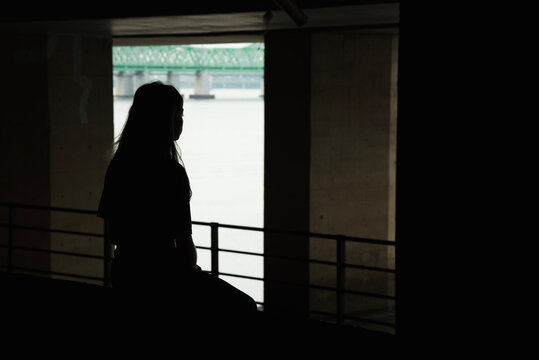 A young woman looking outside under the bridge