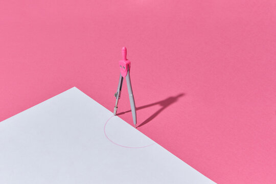 Compass drawing a half-circle on white paper.
