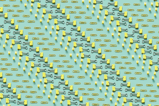 Pattern of yellow binders, push pins and paper clips.