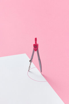 Compass drawing a half-circle on white paper sheet.