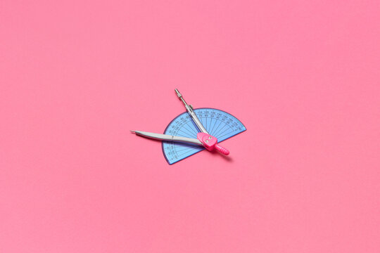 Compass and protractor on pink background.