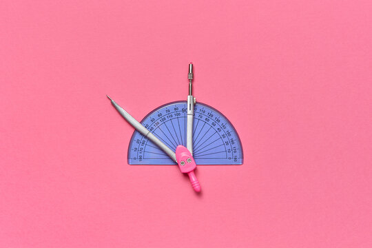 Compass and protractor against pink background.