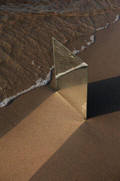 The mirror on the sand next to the edge of sea water wave.