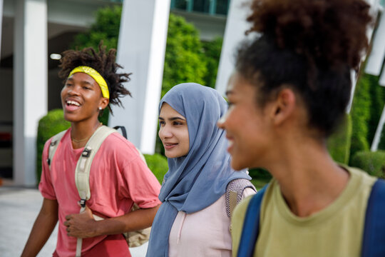 Group of student friends, two girls and one boy having fun outdoors