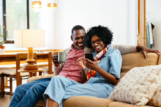 Cheerful couple using smartphone in a bright home