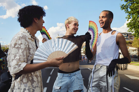 Three queer friends confidently walk down the street during gay pride
