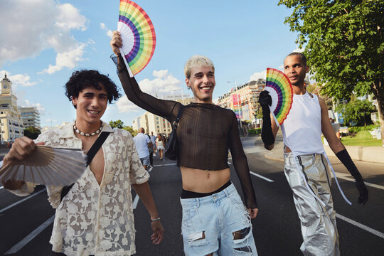 Three queer friends confidently walk down the street during gay pride