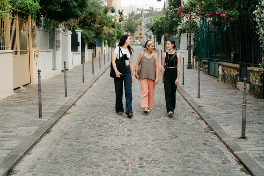 mother and her two daughters walking in a street in Paris France