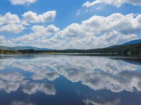 Blue sky with clouds reflection in Ribnicko lake on Zlatibor mountain