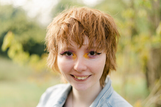 portrait of happy young woman with fun & colorful make up 