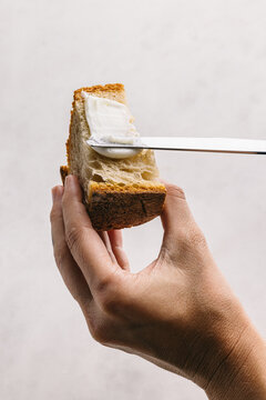 Crop person spreading butter into a slice of bread