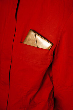 Close-up of a person wearing red shirt and golden wallet in a pocket