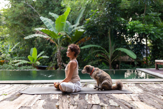 Woman meditating next to the swimming pool