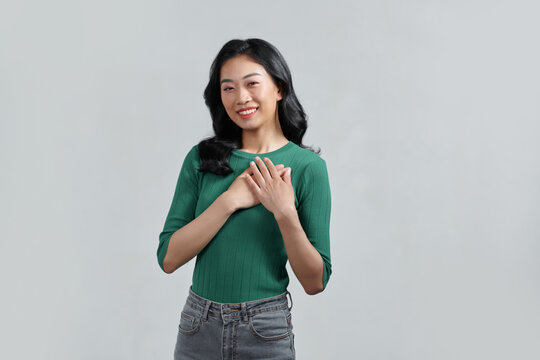 Happy mindful thankful young woman holding hands on chest smiling 