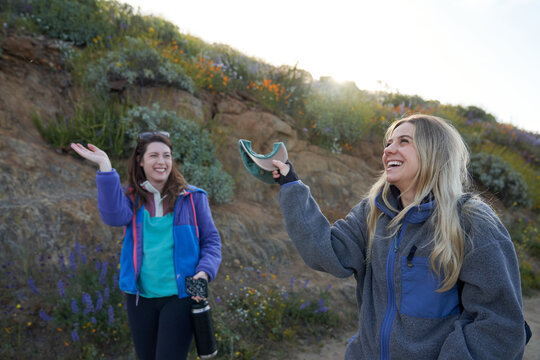 A blonde and brunette wave bugs away on a trail