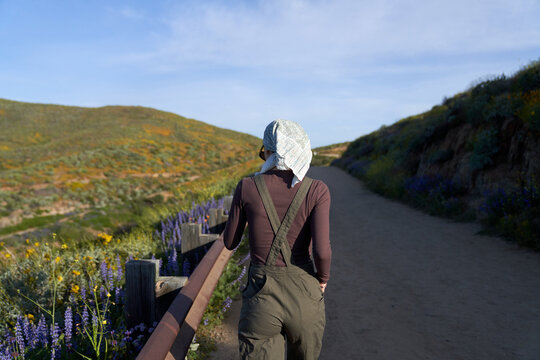 A muslim girl in green overalls walks a trail in nature