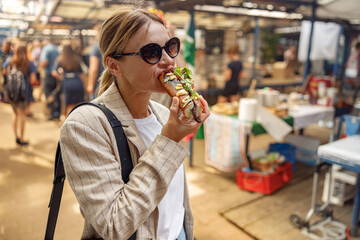 Woman freelancer is having a takeaway fast food lunch on food market