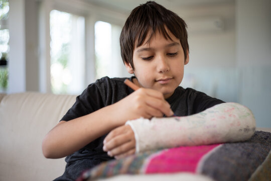 Kid with broken arm writing his name on his cast