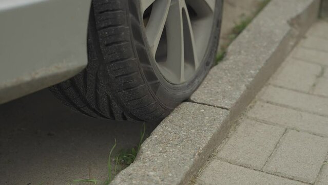 Close up of a badly parked car with tyre on curb. Careless parking along road. Car wheel on pavement, in 4K, 30fps.